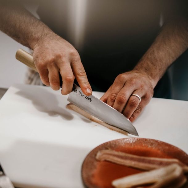 chef qui coupe au couteau japonais un filet de hareng